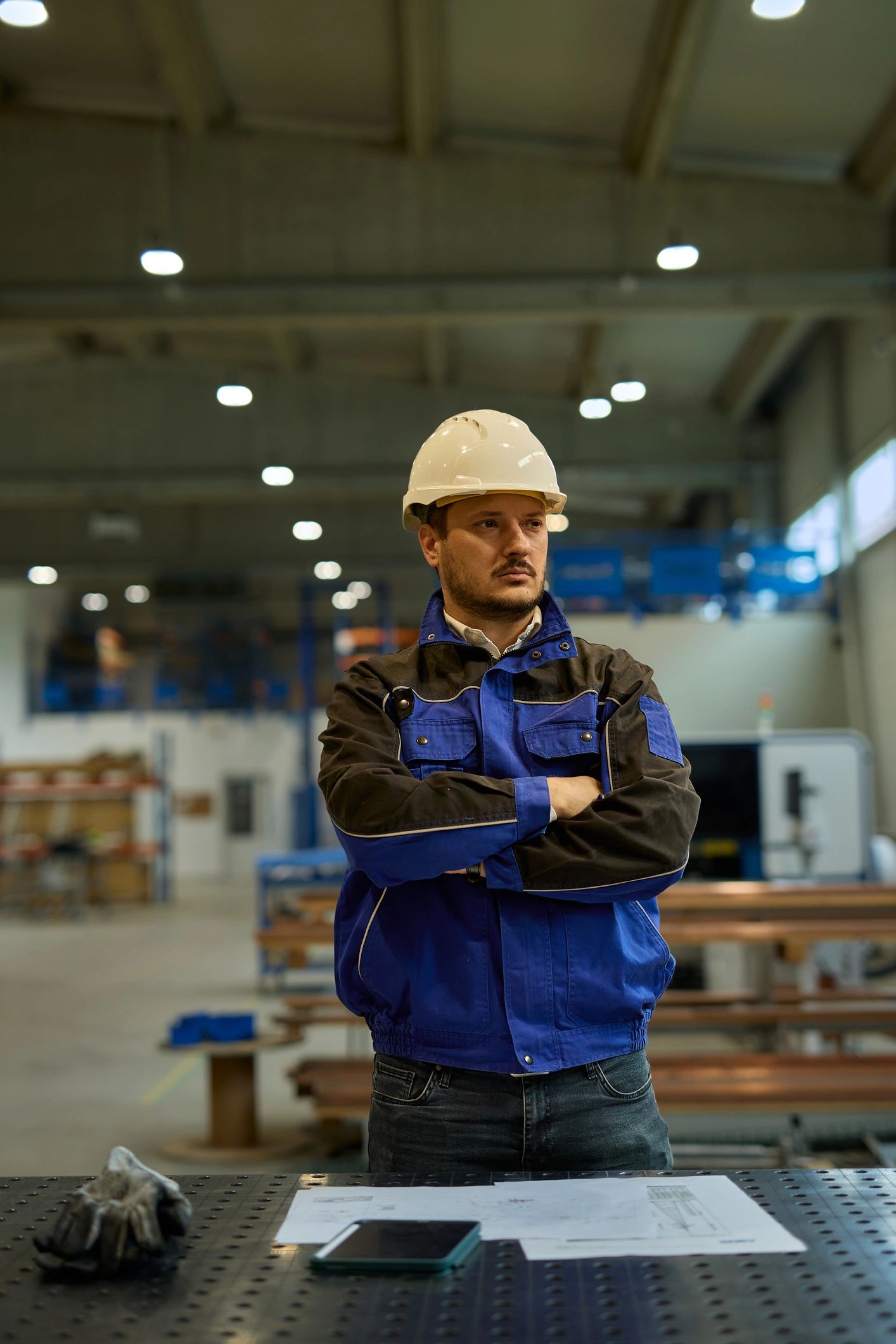 Confident Factory Engineer Standing With Hard Hat and Arms Crossed on Industrial Workshop Floor